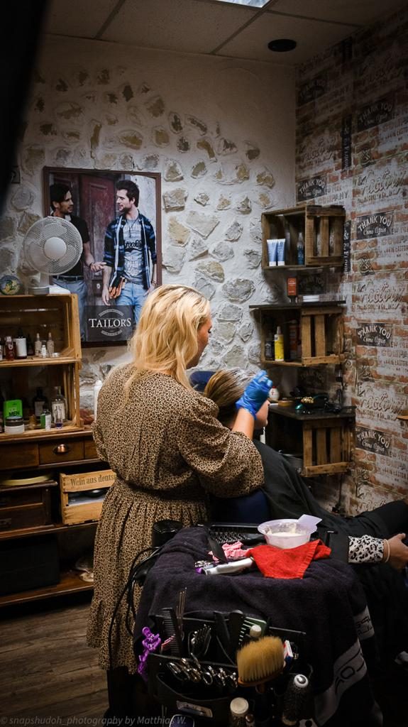 Der Salon mit Natursteinwand, Holzregalen und Frisierplatz